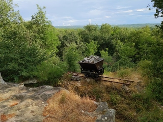 [Wagonnet de carrière abandonné devant un paysage verdoyant]